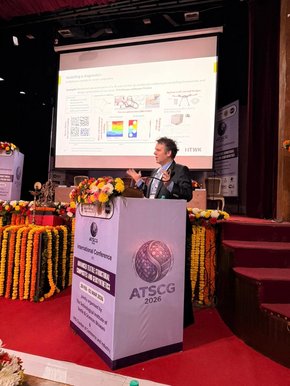 Keynote-Vortrag auf der ATSCG 2026 Prof. Robert Böhm steht auf einer Konferenzbühne und hält einen Vortrag. Im Hintergrund ist eine Präsentationsfolie zu sehen.