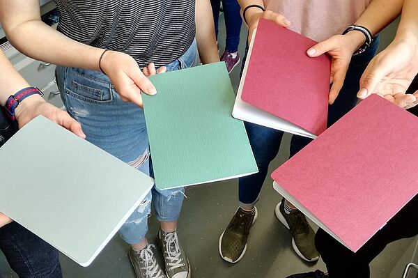 Hände zeigen vier selbstgemachte Hefte aus Papier