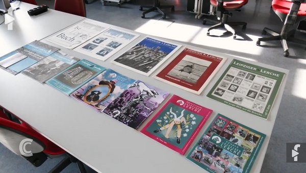 Mehrere Titelseiten ausgewählter Herausgaben der "Leipziger Lerche" liegen präsentiert auf einem Tisch. 