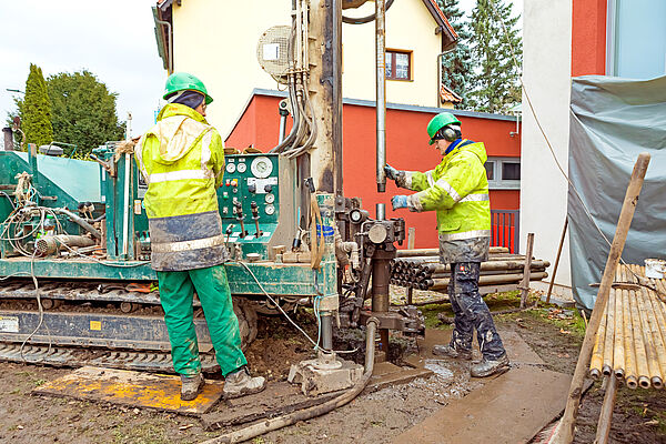 zwei Männer stehen im Matsch am schweren Gerät