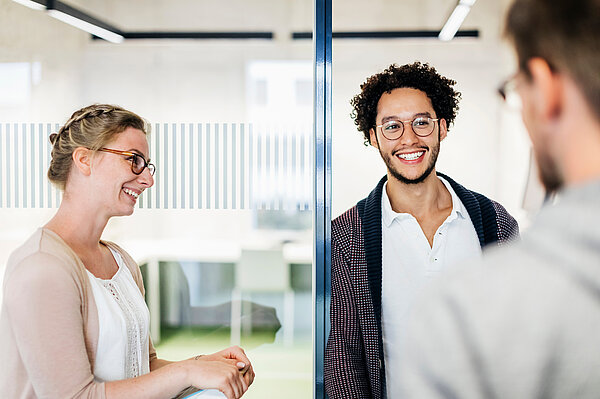 drei Studierende unterhalten sich vor einem der Arbeitsräume