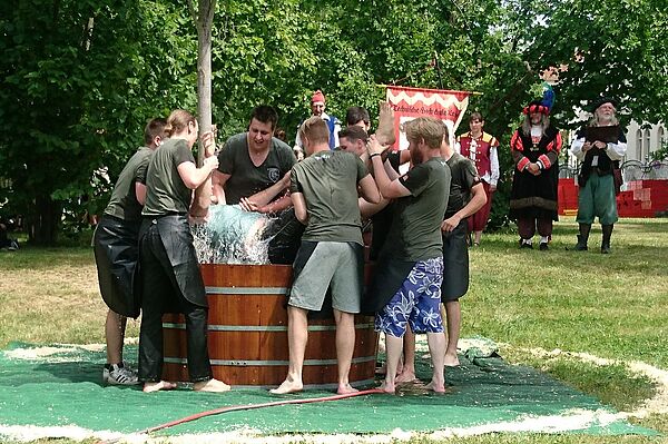 Eine Person wird festgehalten und in ein Becken voller Wasser getaucht