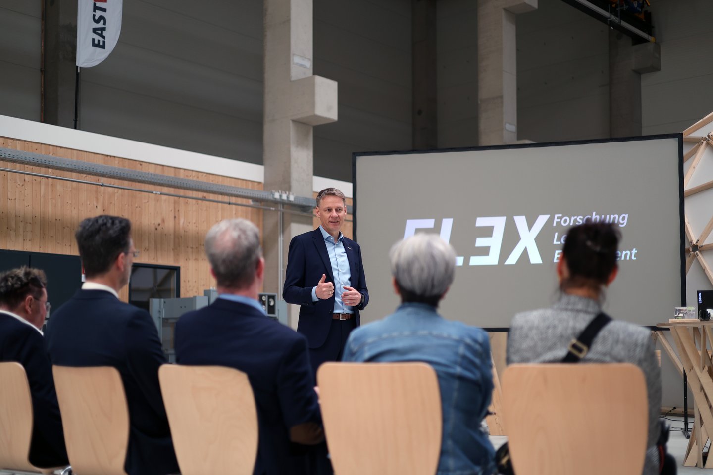 ein Mann hält einen Vortrag in einer Holzhalle