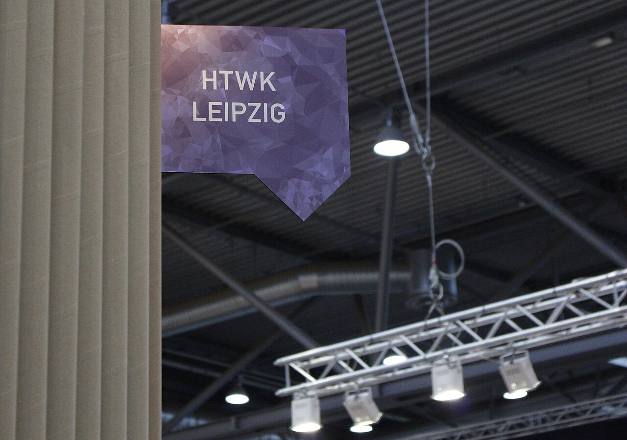 an einer Wand aus aufgestollten großen Pappröhren hängt ein Schild mit der Aufschrift "HTWK Leipzig"