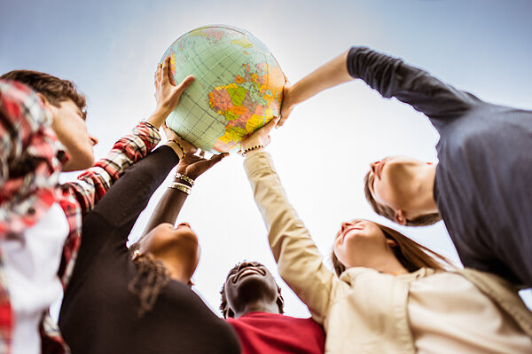 Internationale Studierende heben Weltkugel in die Luft