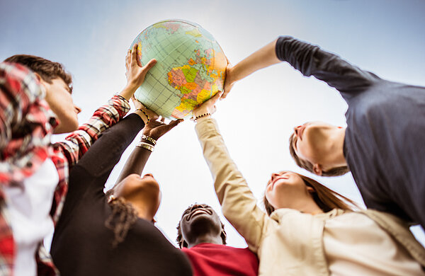 Internationale Studierende heben Weltkugel in die Luft