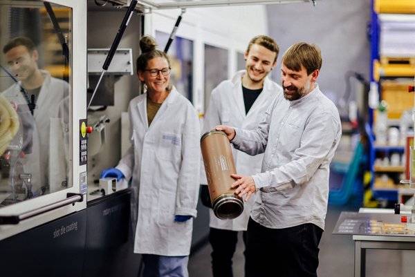 Prof. Ingo Reinhold (re.) forscht mit seinem Team auf dem Gebiet von 3D-Druck und Beschichtungen. (Foto: Anne Schwerin/HTWK Leipzig) drei Personen in technischer Umgebung