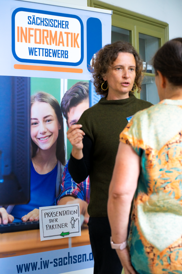 Marcella Pineda De Castro, Projektmitarbeiterin bei den RoboCreators der HTWK Leipzig Frau vor einem Bild im Gespräch mit einer Person