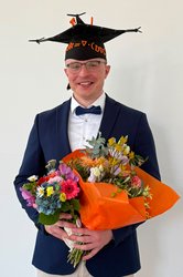 Portraitfoto mit Doktorhut und Blumenstrauß