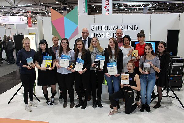 Ein Gruppenfoto mit vielen Studierenden, sie halten Bücher in den Händen