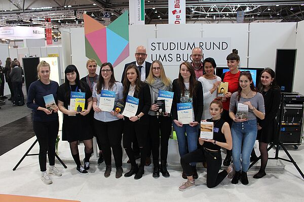 Ein Gruppenfoto mit vielen Studierenden, sie halten Bücher in den Händen