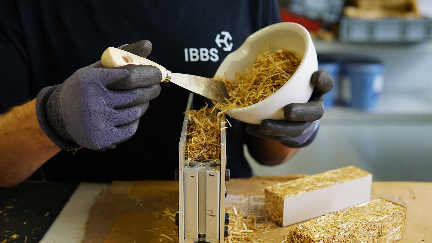 Ein Mann füllt Stroh in eine Schalung