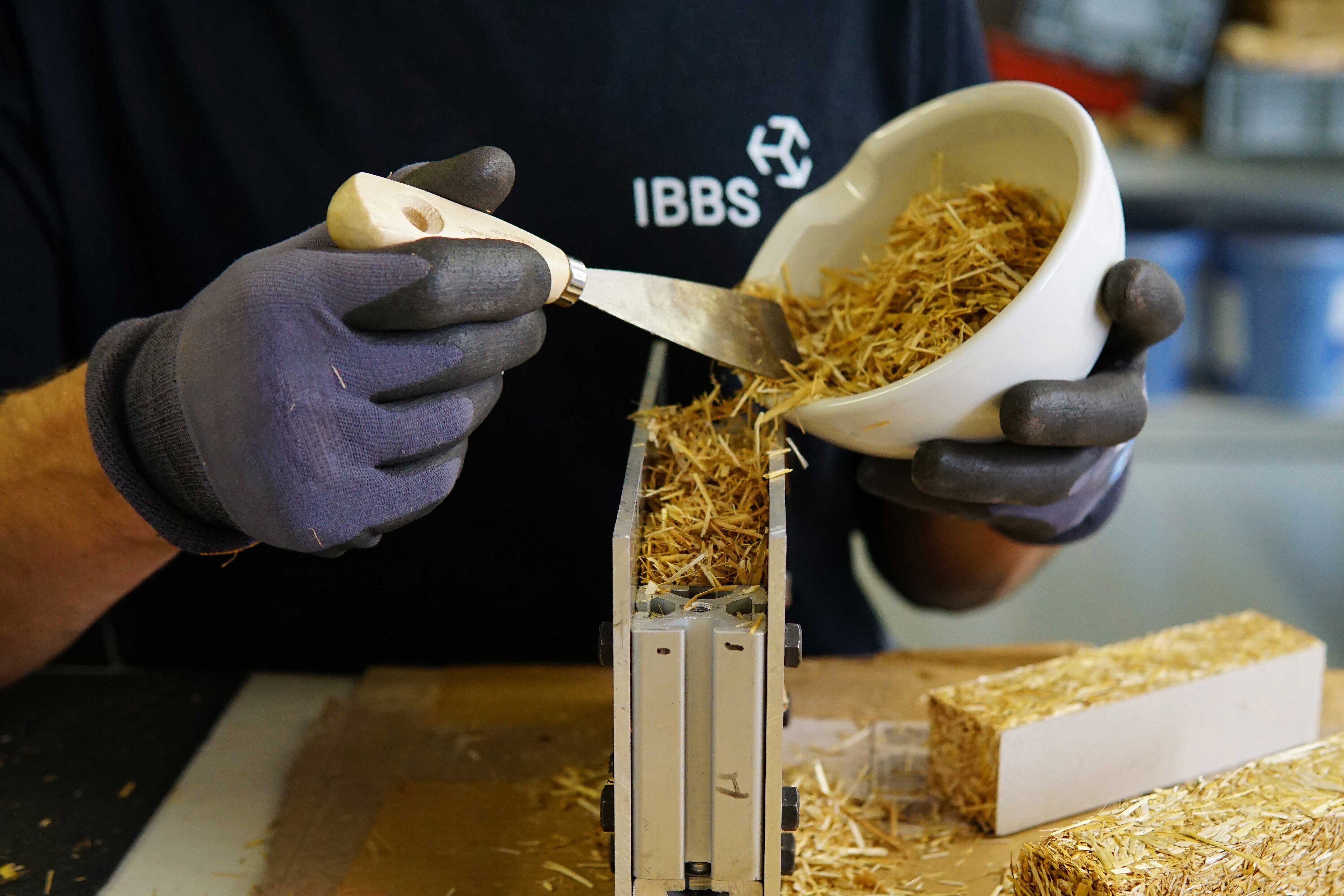 Ein Mann füllt Stroh in eine Schalung