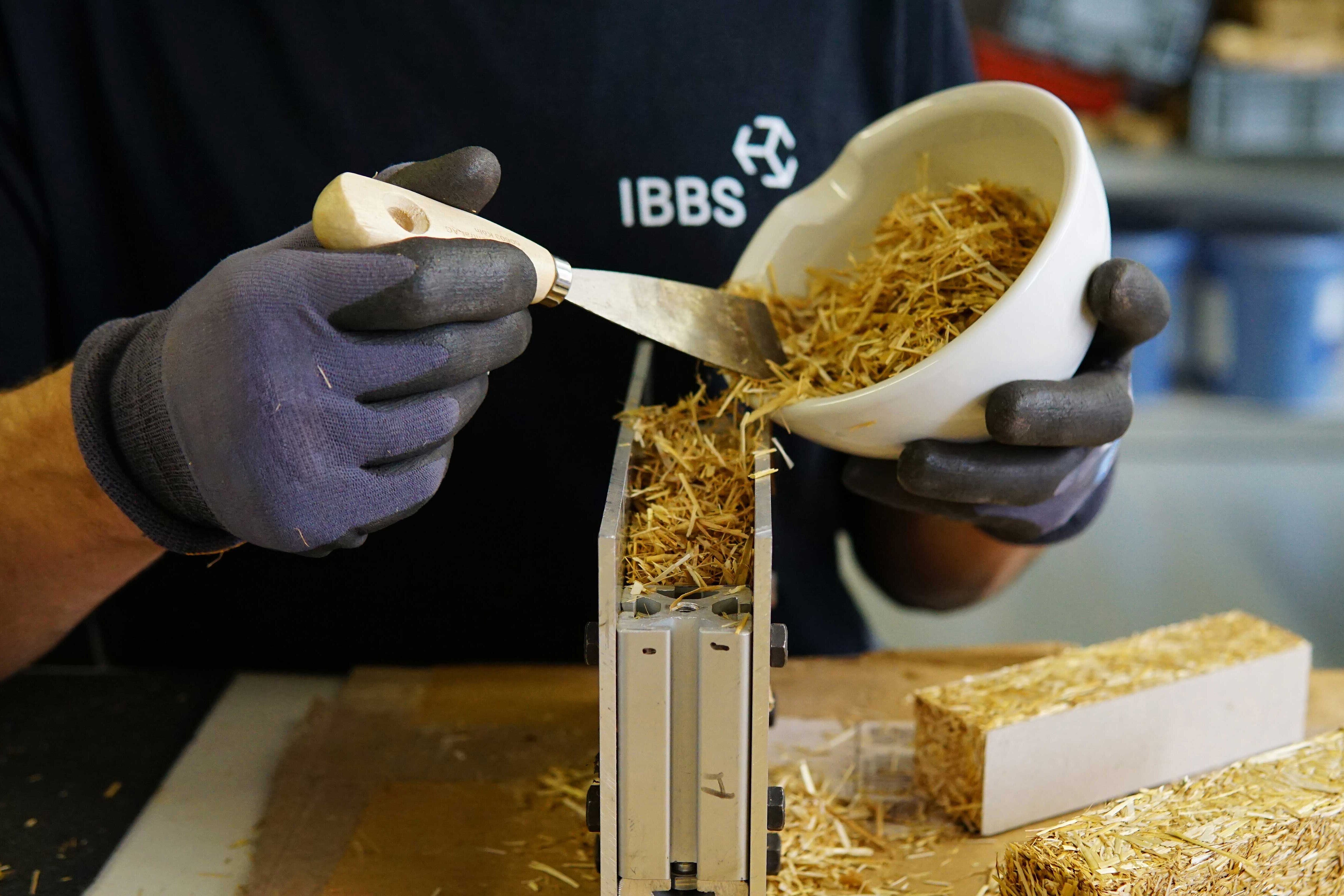 Ein Mann füllt Stroh in eine Schalung