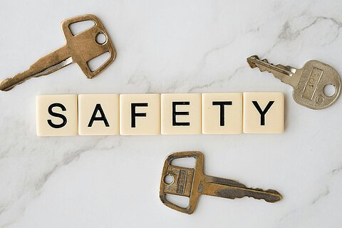 Auf einem Tisch liegen Schlüssel und Buchstaben, die das Wort SAFETY bilden