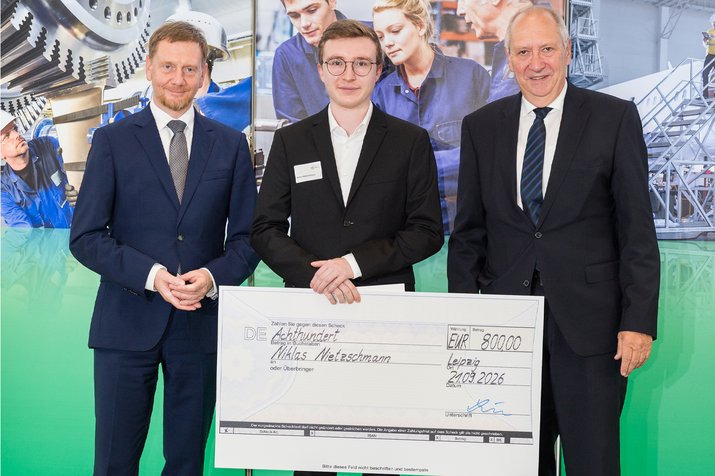 Gruppenfoto, Preisträger in der Mitte hält riesigen Scheck zwischen den Händen