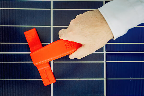 Das rote Handgerät sieht auf den ersten Blick aus wie ein Scheibenabzieher. Tatsächlich ist es aber ein Messgerät, das Solarmodule auf ihre Funktionalität prüft. (Bild: Stephan Flad / HTWK Leipzig)