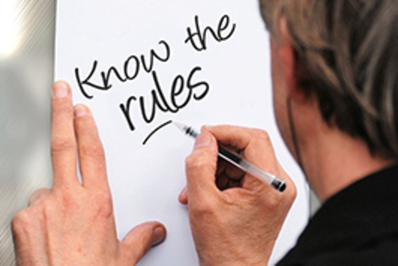 A man is writing "Know the rules" on a paper