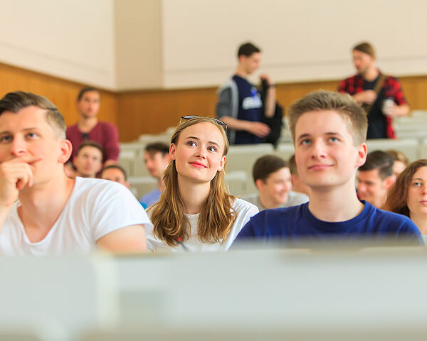 Illustration: Studierende sitzen in einem Hörsaal und lauschem dem Vortrag.