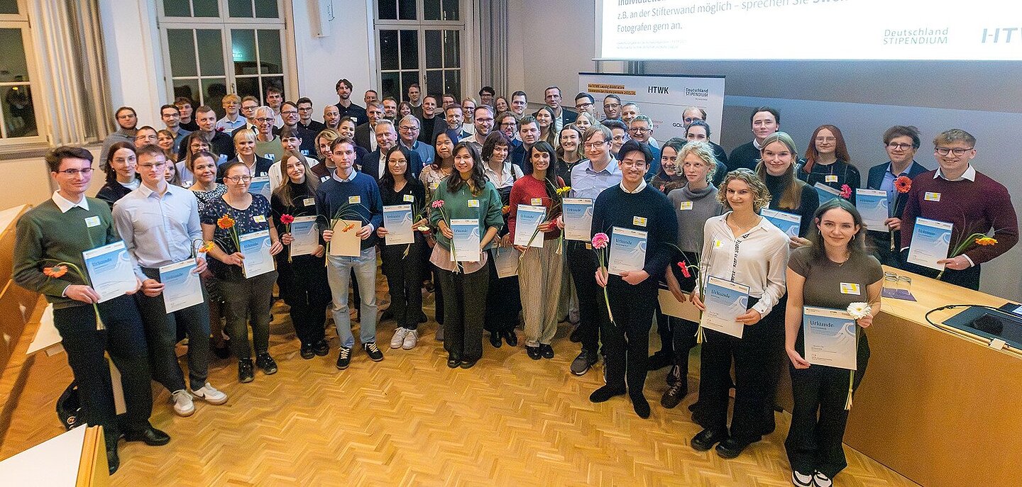 eine große Gruppe von Menschen in einem Hörsaal steht im Halbkreis