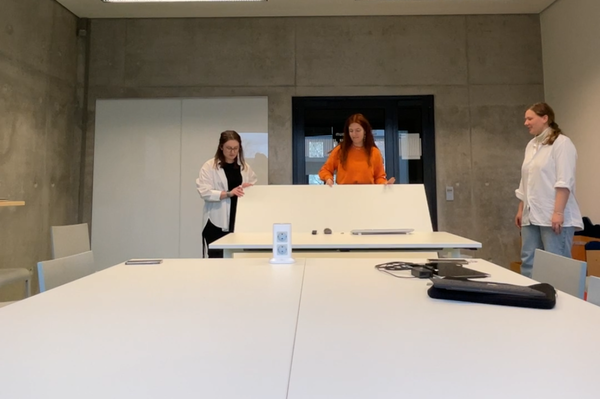 3 Studentinnen räumen im Gruppenarbeitsraum die mobilen Tische um
