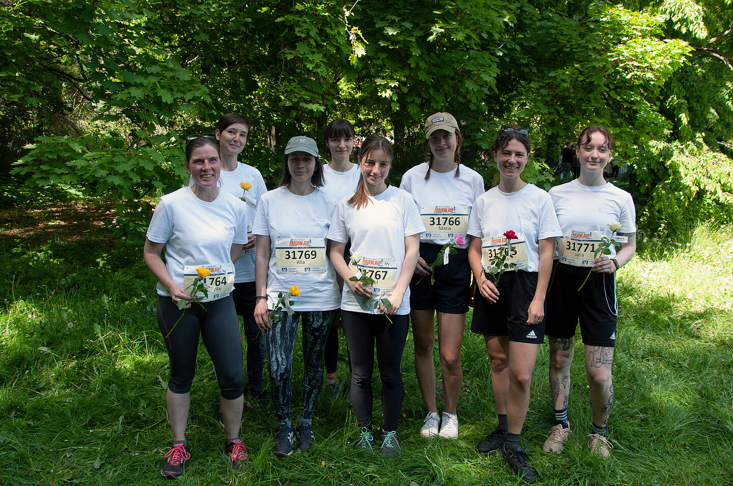 8 Frauen mit Startnummern und Sportsachen und Blumen