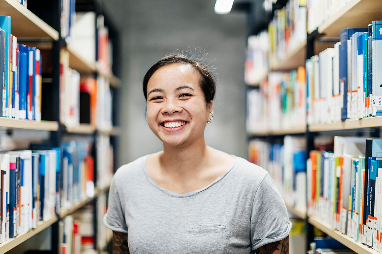 Smiling student between book shelves