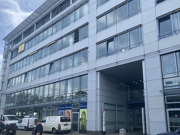Ein sechsstöckiges, silbernes Gebäude mit vielen Fenstern. Durch einige Fenster im ersten Stock sieht man einige Buchregale. In dem Gebäude befindet sich unter anderem die Stadtteilbibliothek Volkmarsdorf.