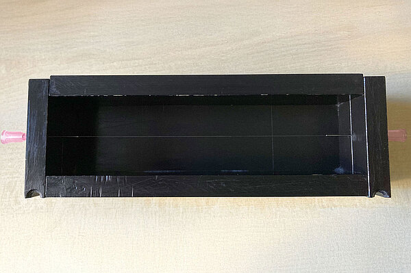 ein schwarzer Kasten mit einer gespannten Glasfaser