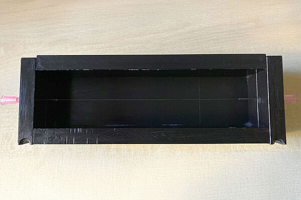 Versuchsaufbau ein schwarzer Kasten mit einer gespannten Glasfaser