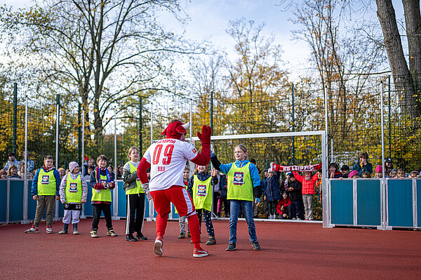 ein Stiermaskottchen klatscht mit einem Schüler ein