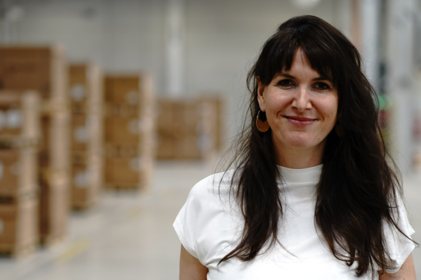 Portrait mit Oberkörper von Anna Förster. Sie steht in einer Lagerhalle.