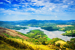 DINOBBIO A green, mountainous landscape with a lake and a blue sky