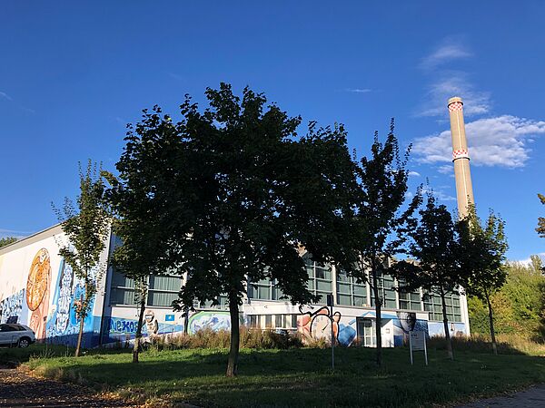Turnhalle hinter Bäumen, rechts daneben Schornstein