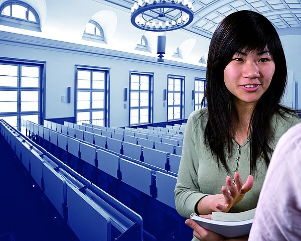Eine internationale Studentin diskutiert mit einer anderen Studentin im Hörsaal.