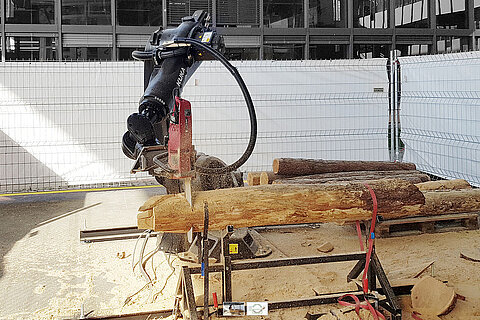 Industrieroboter bearbeitet Holzstamm mit einer Säge