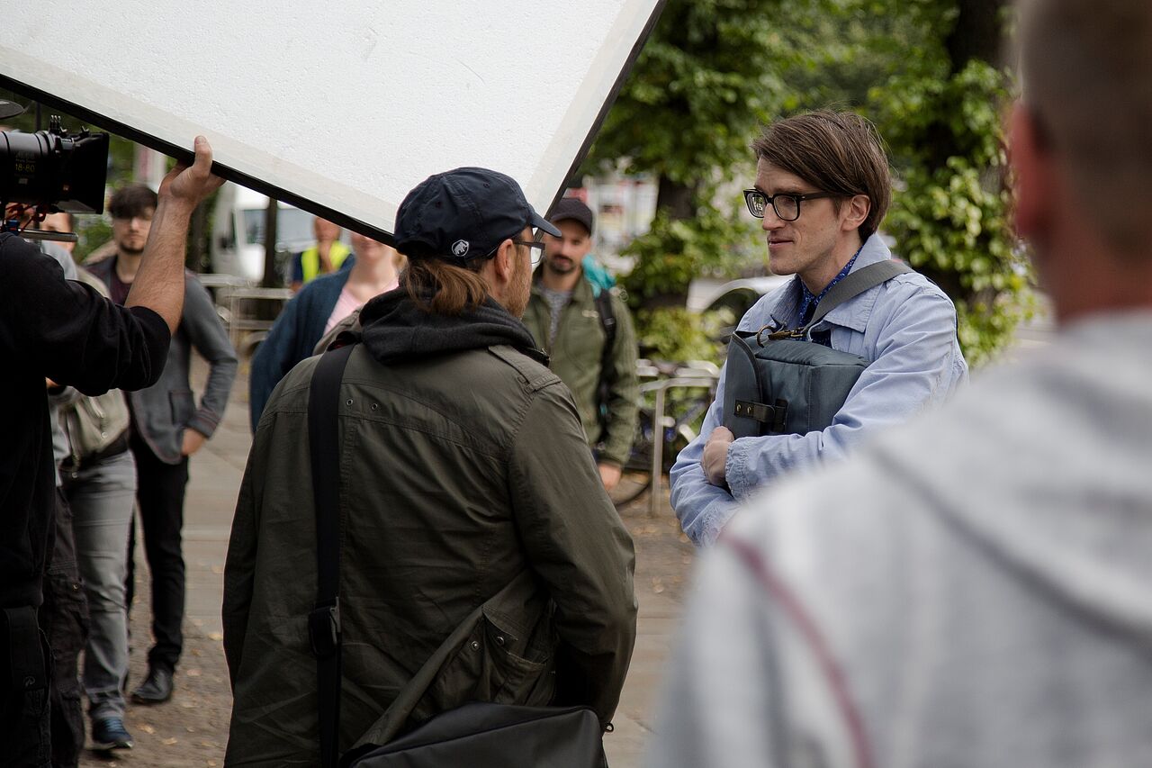 Regisseur Jörg Mielich spricht mit Hauptdarsteller Daniel Steiner, im Hintergrund hält jemand eine weiße Blende