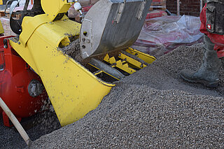 Rekarbo-Screed A shovel fills a machine with mixtures of materials