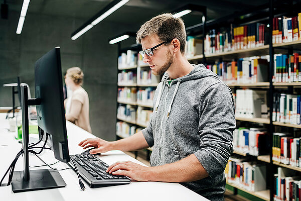 Student arbeitet in der Bibliothek am PC-Bildschirm