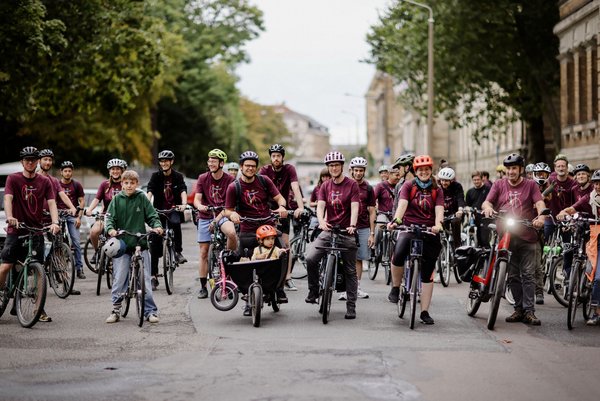 Gruppe von Radelnden in beerenfarbenen T-Shirts