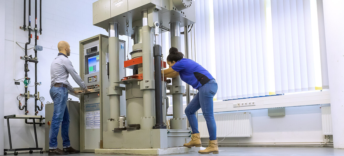 Zwei Personen bedienen eine große Maschine im Labor