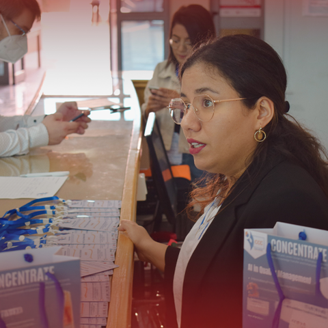 Sarah sitzt am Empfangscounter, Seitenportrait, sie spricht mit jemandem, der nicht zu sehen ist