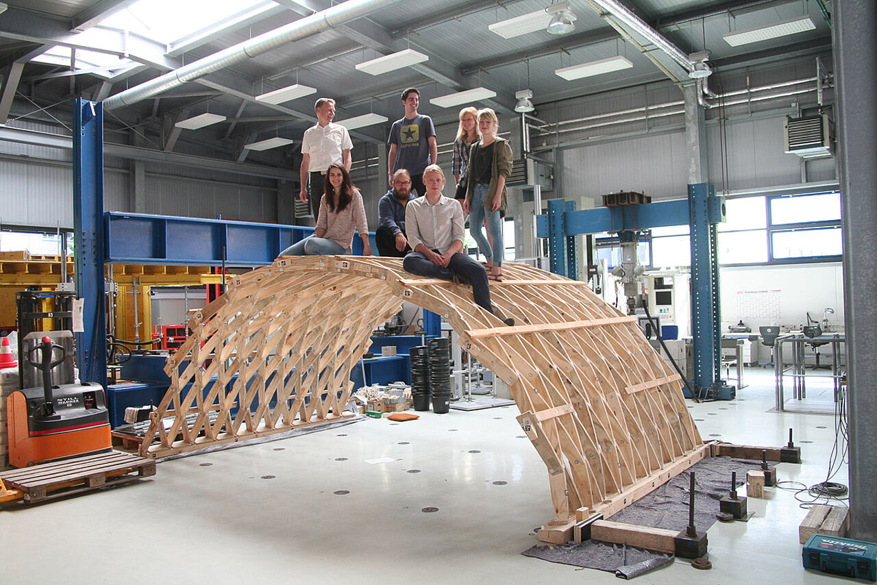 Several people on the wooden construction of an approx. 2.5 meter high round arch