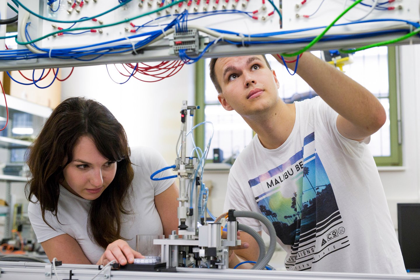 Two people work on the electrics in a workshop