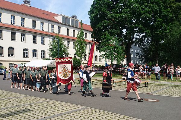 Eine Gruppe Menschen läuft mit Fahnen über den Hof