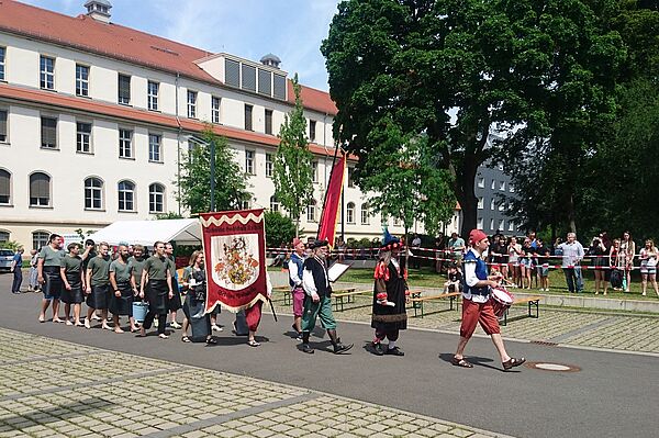 Eine Gruppe Menschen läuft mit Fahnen über den Hof