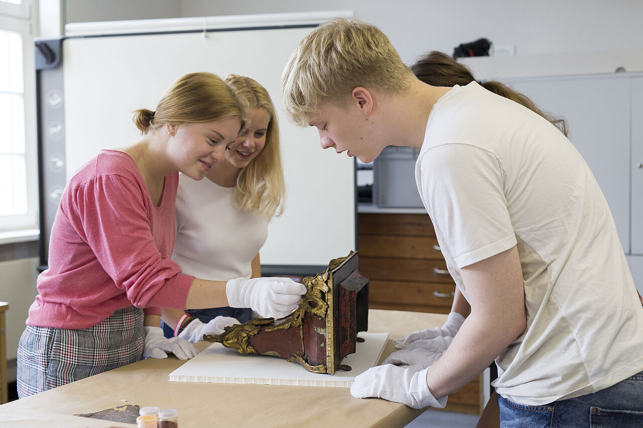 Drei Studierende untersuchen eine Wandkonsole im Labor Bestandserhaltung des Studienganges Museologie.