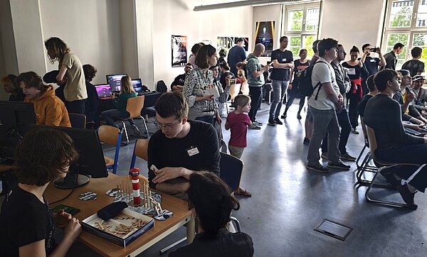 Video- und Brettspiele locken Groß und Klein zur LNC. (Foto: HTWK Leipzig) Viele Menschen in Seminarraum spielen zusammen verschiedene Spiele