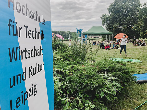 blau weißer Roll Up Banner mit Schriftzug Hochschule für Technik, Wirtschaft und Kultur Leipzig, im Hintergrund der Richard Wagner Hain in Leipzig