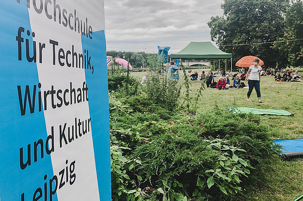 blau weißer Roll Up Banner mit Schriftzug Hochschule für Technik, Wirtschaft und Kultur Leipzig, im Hintergrund der Richard Wagner Hain in Leipzig